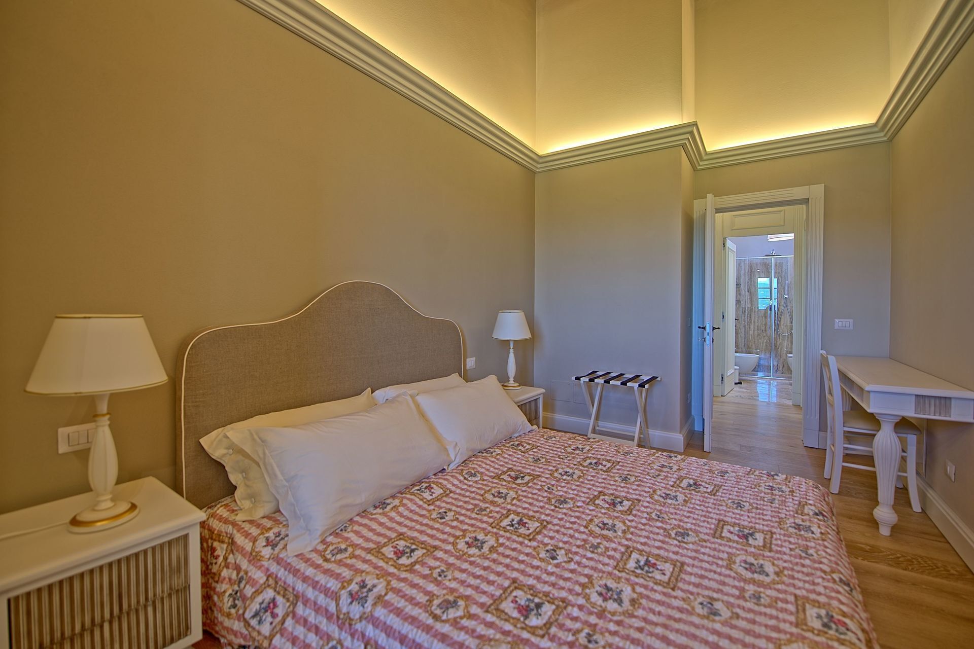 Un dormitorio con cama, lámparas de noche, una mesita y vistas al baño.