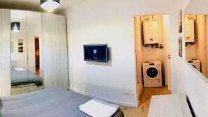 Ein kleines Schlafzimmer mit einem Bett, einer Waschmaschine und einem Heizgerät.