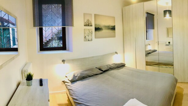 Ein Schlafzimmer mit Bett, Nachttisch, Lampe und einem Kunstwerk an der Wand.