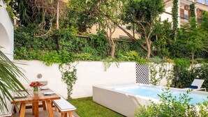 A private garden with a pool, a wooden table with chairs, and a small table with a vase of flowers. - Jacaranda House - My Rental Homes (Sant'Agnello)