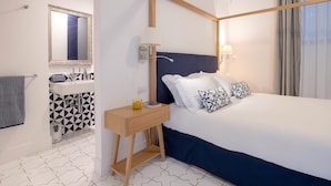 A hotel room with a bed, bedside table, lamp, and a bathroom with a mirror and sink. - Jacaranda House - My Rental Homes (Sant'Agnello)