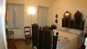 A bedroom with a bed, a chair, a table, and a wall-mounted mirror. - Casa O is a 19th-century, restored, stone house with garden IT046022C2LZ5R4HQX (Pescaglia.)