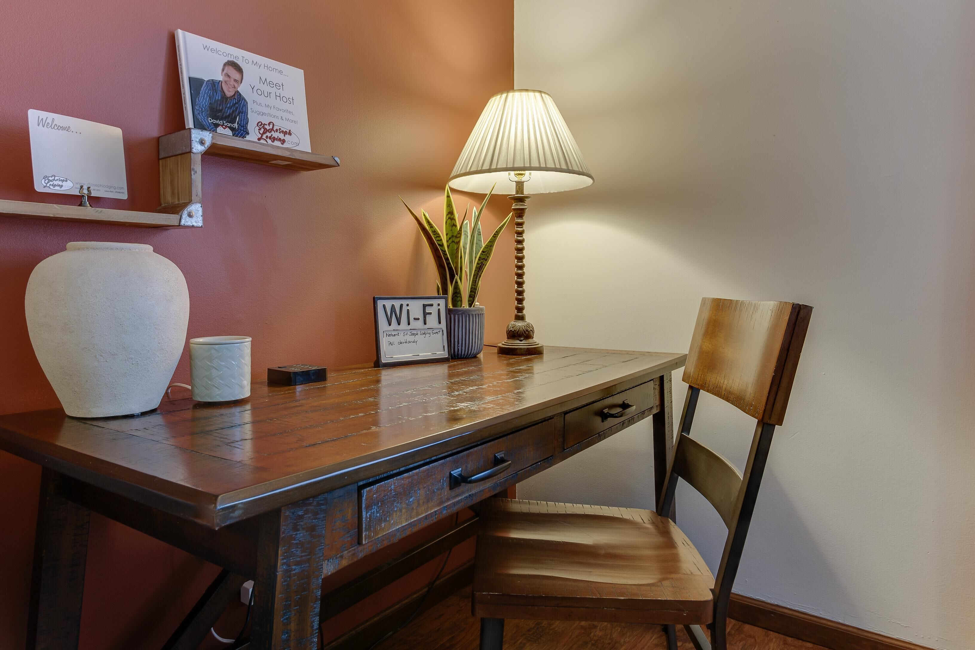 Una scrivania in legno con una lampada, un cartello Wi-Fi, una tazza e un vaso.