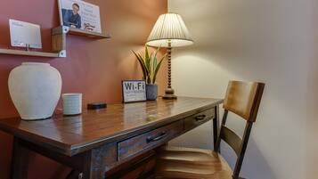 Una scrivania in legno con una lampada, un cartello Wi-Fi, una tazza e un vaso.