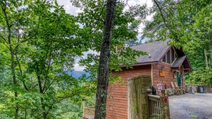Un rustico chalet con facciata in legno, un balcone e un muro in pietra.