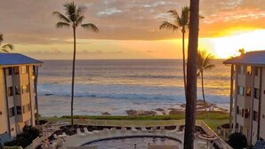 Ein Resort mit Pool, Palmen und Blick auf den Ozean bei Sonnenuntergang.