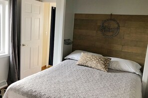 A bedroom with a bed, a headboard, a welcome sign, and a door.