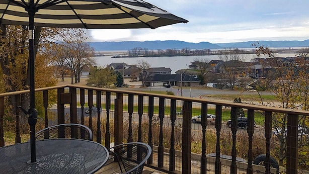 Eine Terrasse mit Tisch und Stühlen mit Blick auf einen See und Häuser.