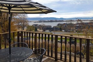 A deck with a table and chairs, overlooking a lake and houses.