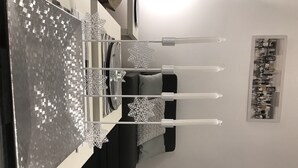 Ein Esstisch mit vier Kerzen, einer schwarz-weißen Tischdecke und einer Schneeflockendekoration.