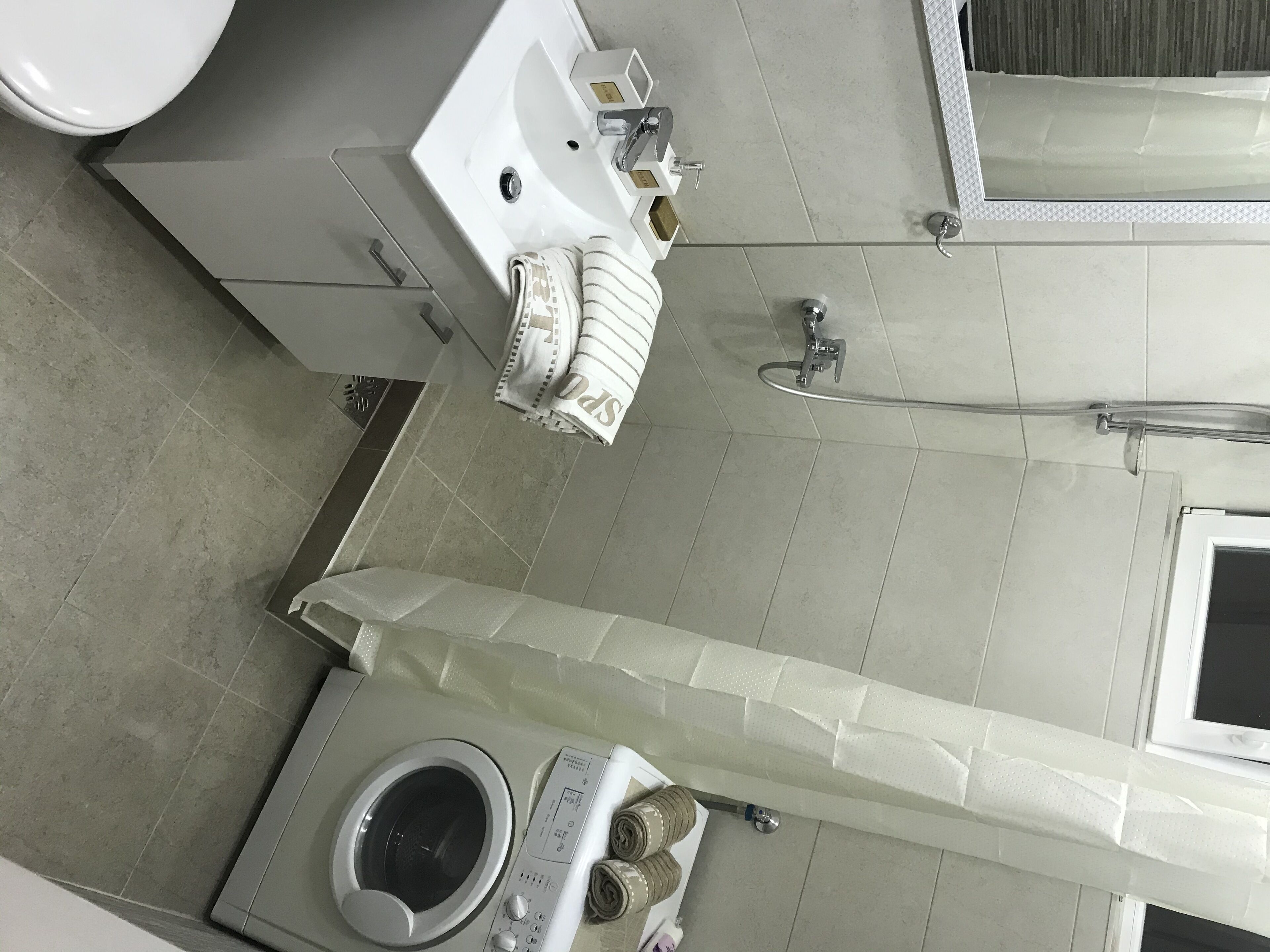 Een badkamer met toilet, wastafel, douche en wasmachine.