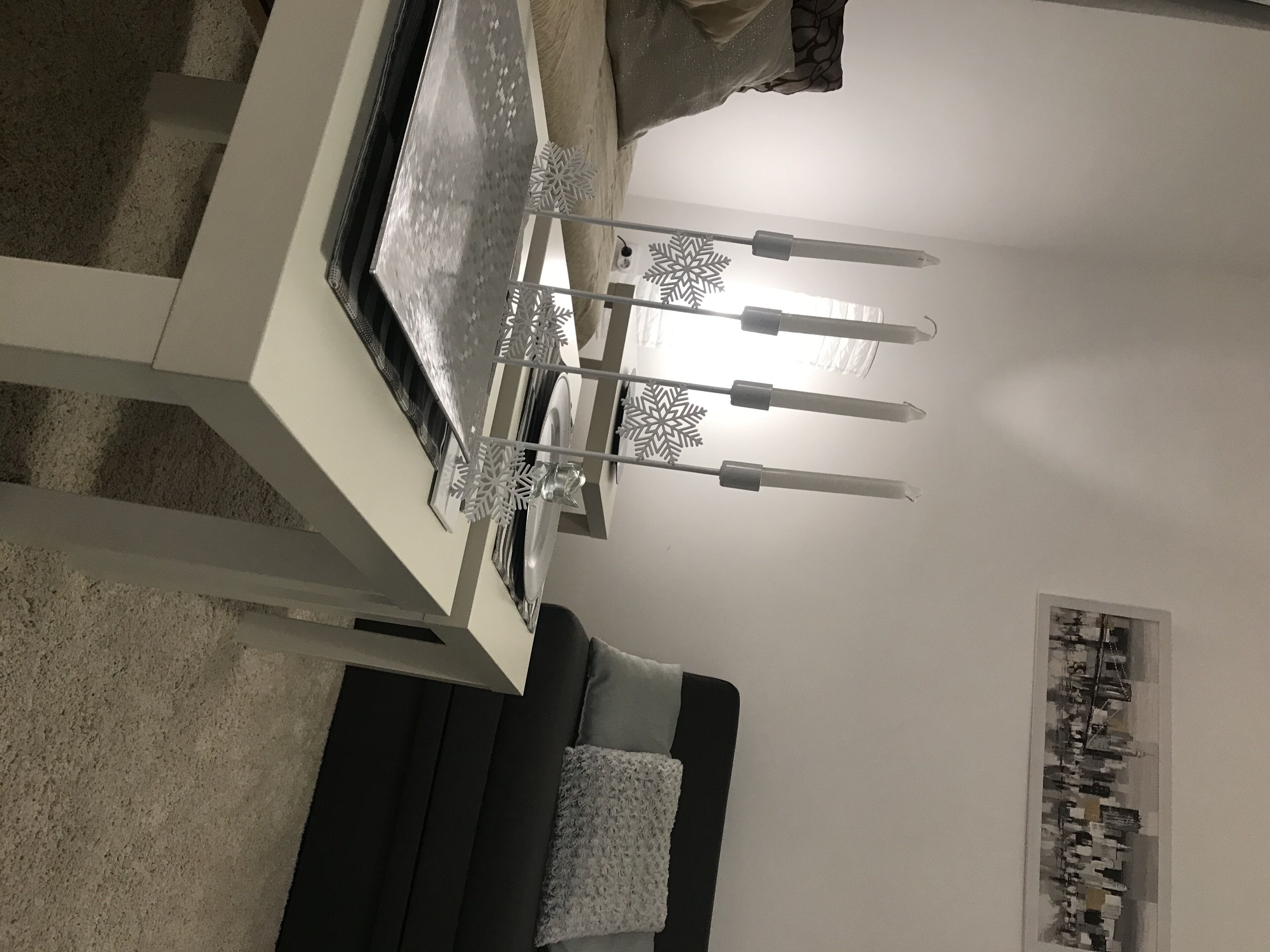 Une table à manger avec un chandelier, un canapé et un mur orné d’un tableau encadré.