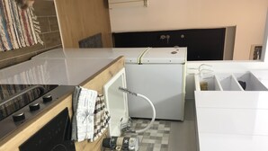Eine kleine Küche mit Herd, Mikrowelle und Kühlschrank.