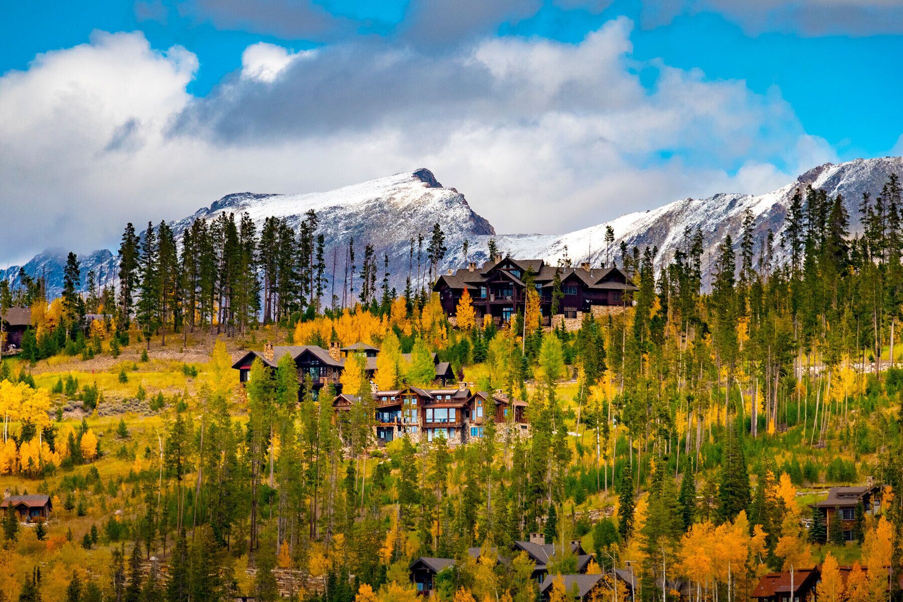 A lodge with multiple buildings surrounded by a forest and mountains.