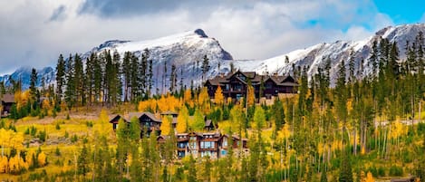 A lodge with multiple buildings surrounded by a forest and mountains.