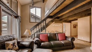 A spacious living room with a leather sofa, a matching ottoman, and a dining area in the background. - Perfect Ski In/Ski Out Condo in Center Village (Copper Mountain)