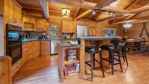 A wooden cabin interior with a kitchen, dining area, and bar seating. - Spacious cabin on beautiful Caribou Lake (Lutsen)