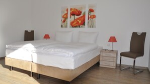 Une chambre à coucher comprenant un lit, deux tables de chevet, une chaise et trois tableaux accrochés au mur.