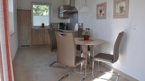 Une cuisine moderne avec des meubles en bois, une hotte en acier inoxydable et un coin repas comprenant deux chaises et une petite table.