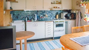 Una cocina con armarios blancos, una estufa, un microondas y una zona de comedor con mesa y sillas.