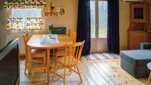 Una habitación acogedora con una mesa de comedor de madera, sillas, un sofá y una ventana con cortinas.