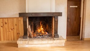 A fireplace with a fire, a wooden door, and a wooden panel wall. - Homerez - Studio in Beaumont-du-Périgord (Beaumont-du-Périgord)