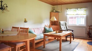 A cozy living room with a wooden dining table, a sofa, a chair, and a lamp. - 2 bedroom amazing home in Burseryd (Burseryd)
