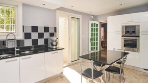 A modern kitchen with white cabinets, a black countertop, and stainless steel appliances.