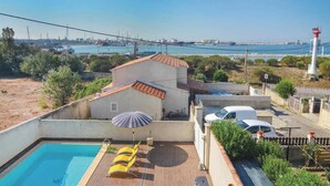 A rooftop pool with yellow chairs and a small house with a tiled roof.