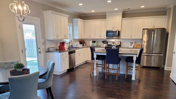 A modern kitchen with white cabinets, stainless steel appliances, and a dark hardwood floor. - Spacious Beautiful home for Masters (Evans)