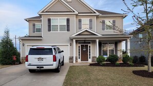 A two-story house with a garage, a driveway, and a well-maintained lawn. - Spacious Beautiful home for Masters (Evans)