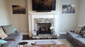 A living room with a fireplace, two sofas, a coffee table, and a television above the fireplace. - Spacious Beautiful home for Masters (Evans)