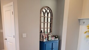 A hallway with a blue cabinet, a white door, and a decorative mirror. - Spacious Beautiful home for Masters (Evans)