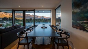 A modern meeting room with a long table, comfortable seating, and large windows offering a mountain view.