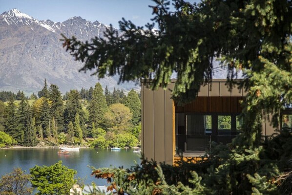 Un edificio moderno con amplios ventanales que dan a un lago y montañas.