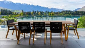 A dining area with a table and chairs, overlooking a lake and mountains.