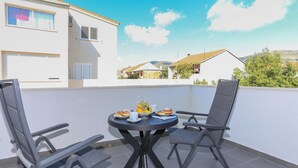 A small round table with two chairs on a balcony with a white wall and a view of houses in the background. - Amazing apartment in Kastel Stari with WiFi (Kastel Stari)
