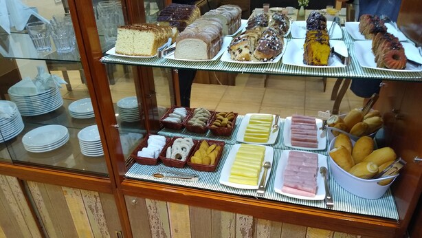 A buffet with various food items including cakes, pastries, and bread. - Pousada Vó Celina (Praia Grande)