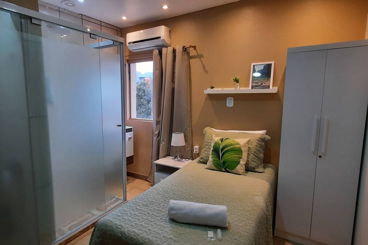Une chambre d’hôtel avec un lit, une armoire, une table de chevet avec une lampe et une fenêtre avec des rideaux.
