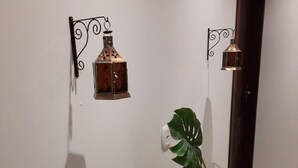 A hallway with a wooden console table holding magazines, a potted plant, and two wall-mounted lanterns. - Pousada Vó Celina (Praia Grande)