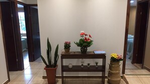A hallway with a wooden console table, potted plants, and a mirror. - Pousada Vó Celina (Praia Grande)