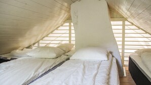 A dormitory-style room with bunk beds and a slanted ceiling. - Amazing home in Gamleby (Gamleby)