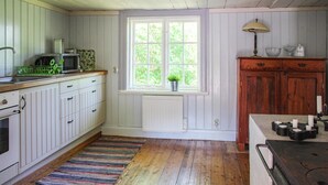 A kitchen with wooden cabinets, a window with a view, a radiator, and a stove. - Amazing home in Gamleby (Gamleby)