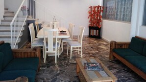 A dining area with a table and chairs, a staircase, a sofa, and a window with curtains. - Hotel Juarez (Cuernavaca)