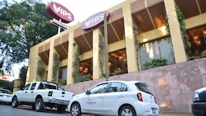 A building with a large 'VIPS' sign, a white car parked in front, and a white truck. - Hotel Juarez (Cuernavaca)