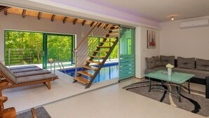 Una sala de estar moderna con una escalera de cristal que lleva a una piscina, un sofá y una mesa de centro.