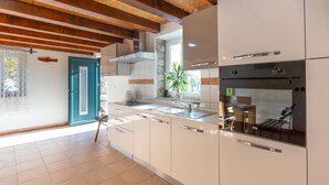 Una cocina moderna con armarios blancos, horno integrado y ventana con vistas al exterior.