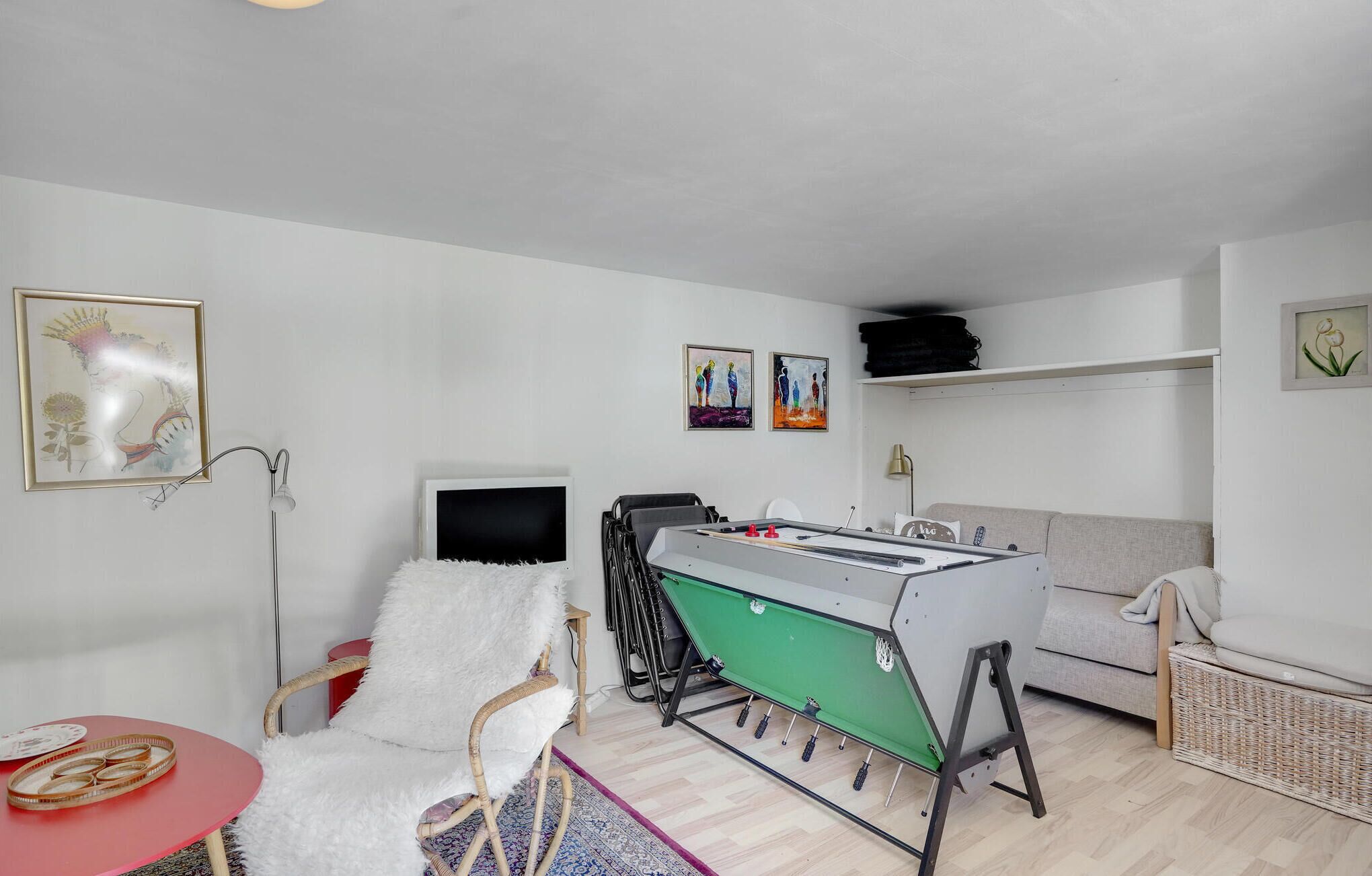 Ein gemütliches Wohnzimmer mit einem Kicker, einer bequemen Couch, einem kleinen Fernseher und einigen Kunstwerken an der Wand.