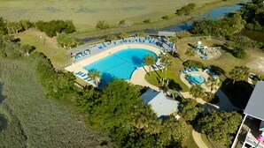 An aerial view of a resort with a large swimming pool surrounded by lounge chairs and palm trees. - Beautiful ocean views all rooms. Very close to beach. Four bedrooms, 3.5 baths. (St. Helena Island)