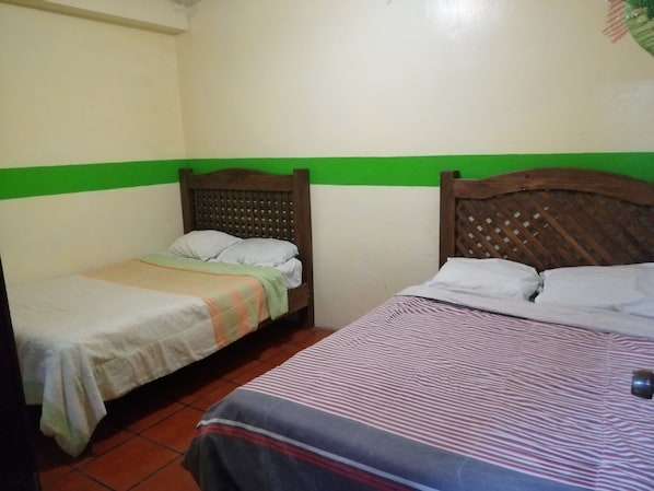 Una habitación con dos camas, una con una colcha a rayas y la otra con una sencilla.
